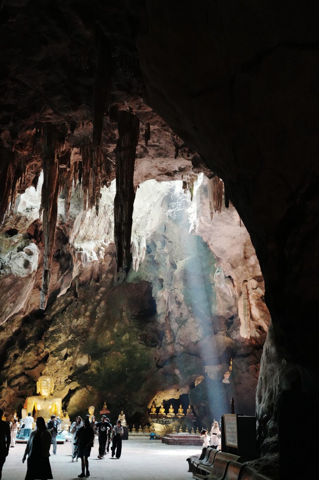 Golden Buddha statues and a beam of light inside Tham Khao Luang cave temple